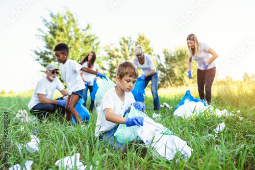 Volunteers with garbage bags cleaning up garbage outdoors - ecology concept.