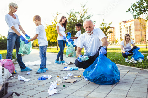 Volunteers with garbage bags cleaning up garbage outdoors - ecology concept.