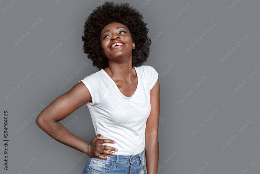 Young woman standing isolated on gray posing hand on hips smiling cheerful Young woman standing isolated on gray posing hand on hips smiling cheerful