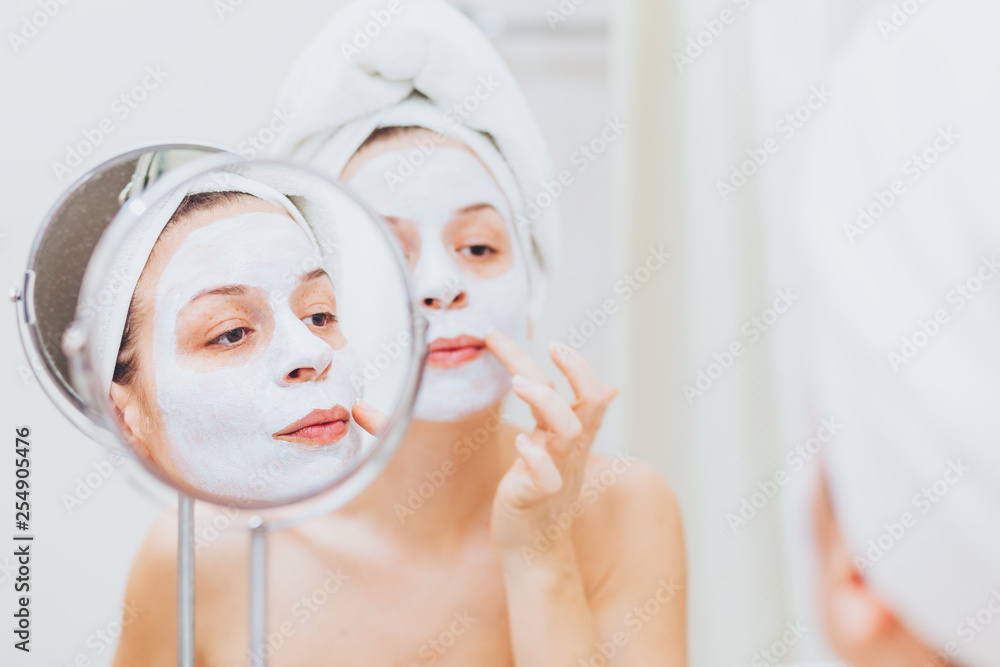 Young woman putting a mask on her face