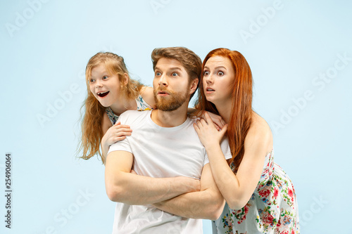 Happy surprised parent with daughter at studio isolated on blue background. Travel, vacation, parenthood, togetherness, tourism concept.