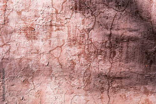 Dirty pink wall with peeling paint and cracks