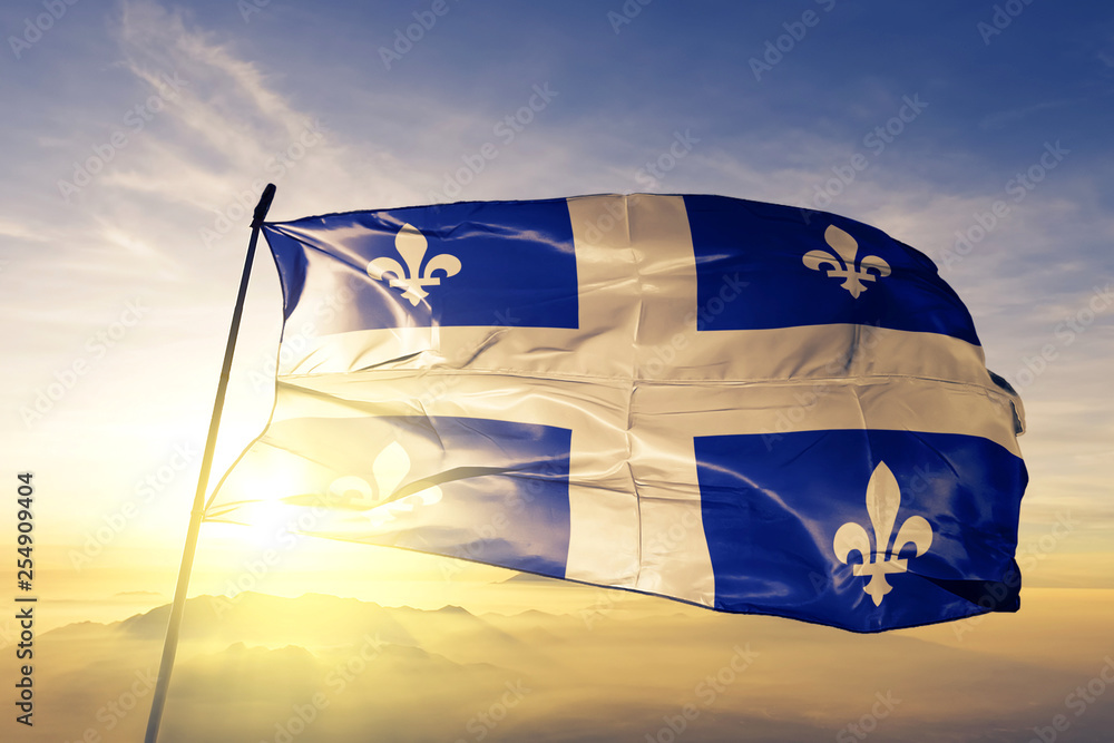 Naklejka premium Flaga prowincji kanadyjskiej prowincji Quebec macha na szczycie mgły o wschodzie słońca