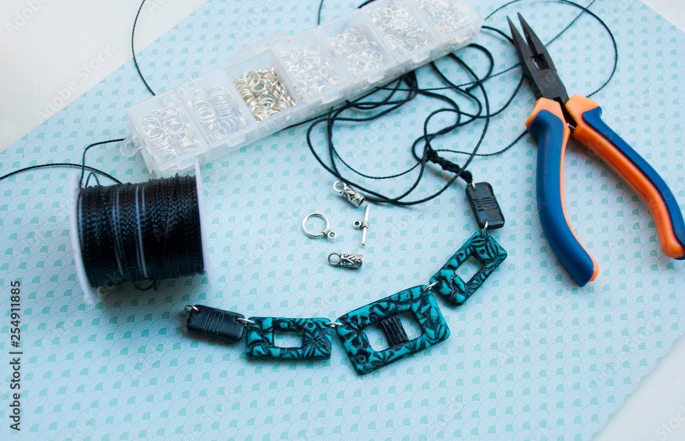 Fototapeta premium Assembly of modern turquoise and black necklace with pliers and another tools. Handmade jewelry.