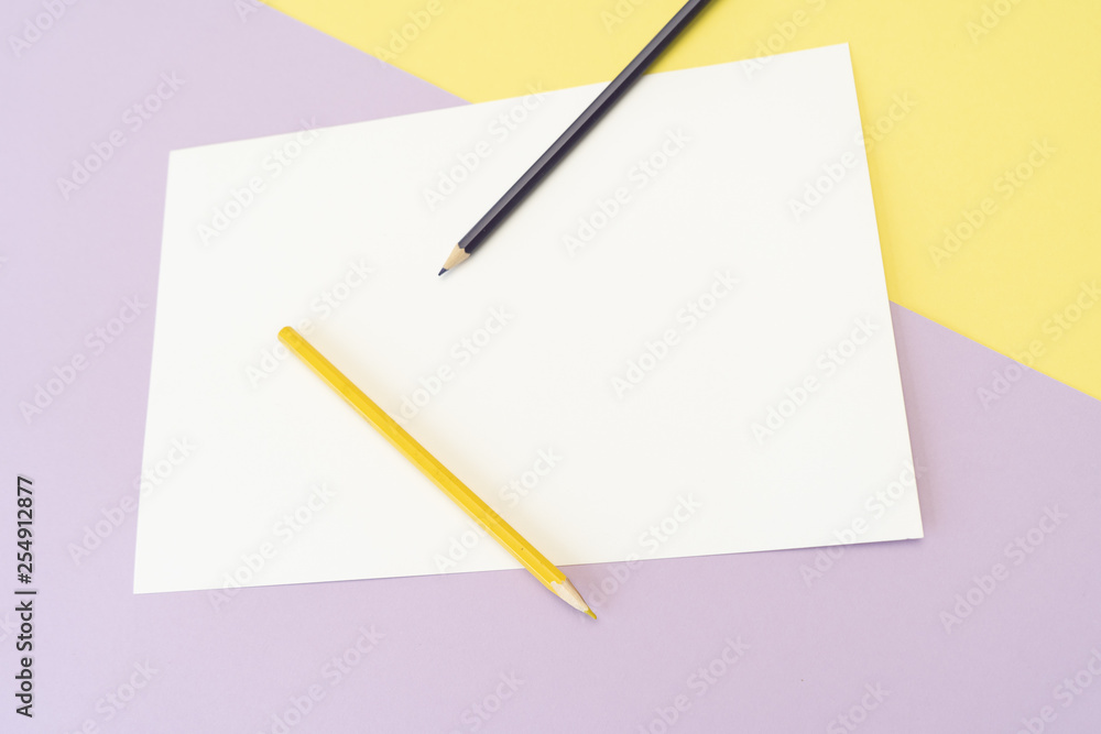 Yellow and purple pencils on the white piece of paper on yellow and purple background. Art, scool or office shoot Yellow and purple pencils on the white piece of paper on yellow and purple background. Art, scool or office shoot