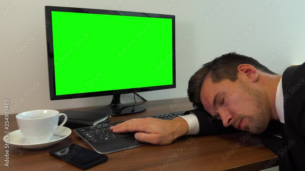 An office worker in a suit sleeps on a desk with a computer with a green screen - closeup An office worker in a suit sleeps on a desk with a computer with a green screen - closeup