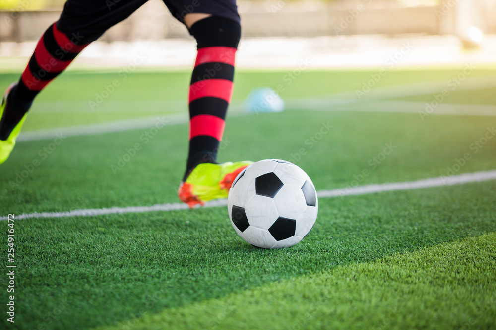 Soccer player speed run to control and shoot ball to goal on artificial turf.