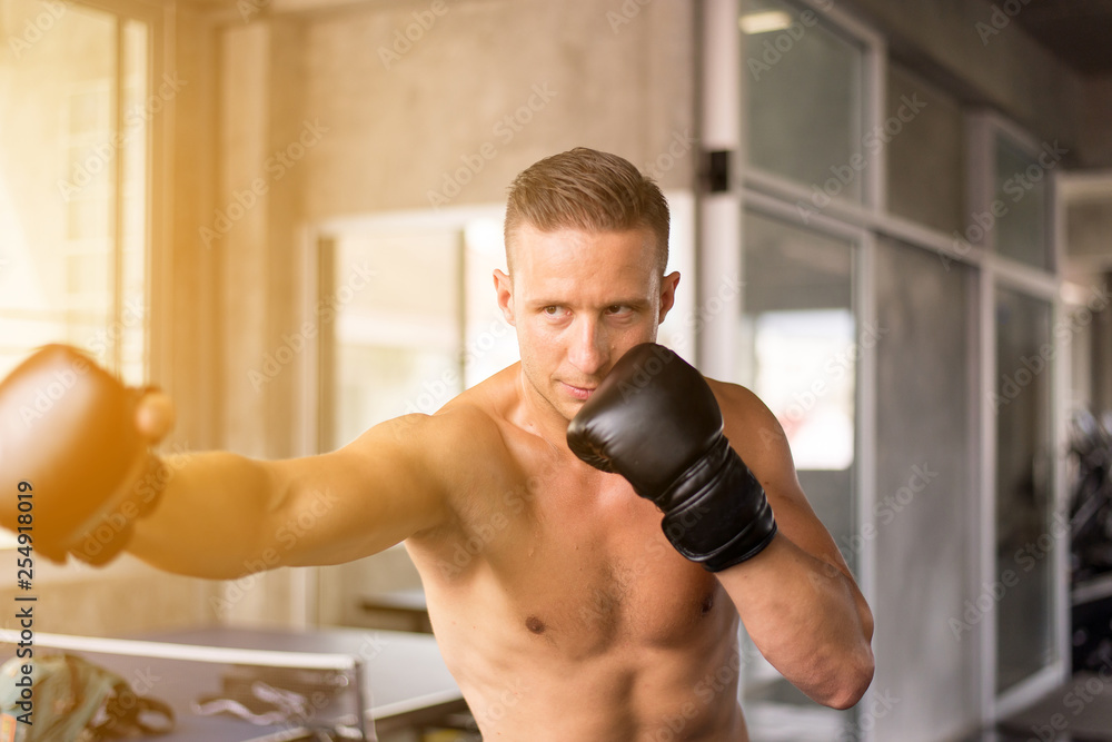 Sporty man boxer posture and punching at a boxing gym,Male boxer eye looking training on punching bag Sporty man boxer posture and punching at a boxing gym,Male boxer eye looking training on punching bag