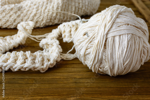 Ball of beige yarn by wool and knitting needles at home on brown wooden table