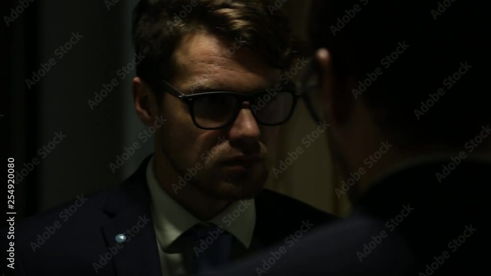 Portrait of a businessman in a business suit. He looks in the mirror straightens his tie. Portrait of a businessman in a business suit. He looks in the mirror straightens his tie.