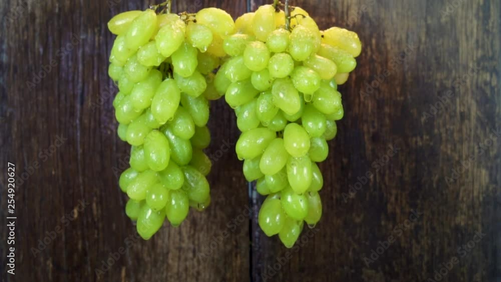 SLOW MOTION: Spay injects water onto a bunch of green grapes. SLOW MOTION: Spay injects water onto a bunch of green grapes.