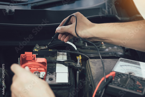 Close up car mechanic is using the car battery meter to measure various values and analyze it.