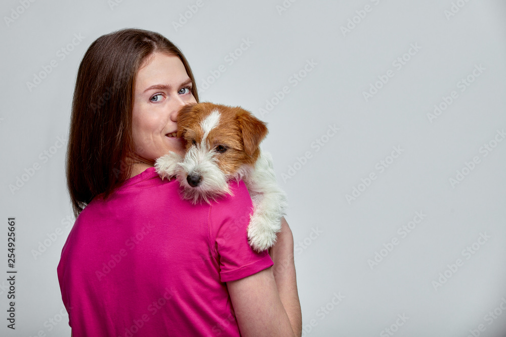 Beautiful girl with a jack russell terrier on her hands on a gray background, copy space Beautiful girl with a jack russell terrier on her hands on a gray background, copy space