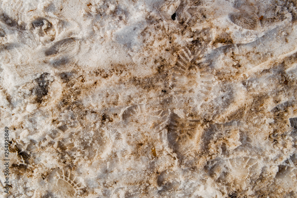 Dirty footprints in the snow in the spring. Footprints in the snow. Snowbreak, thaw. Spring. Snow background. Slush Dirty footprints in the snow in the spring. Footprints in the snow. Snowbreak, thaw. Spring. Snow background. Slush