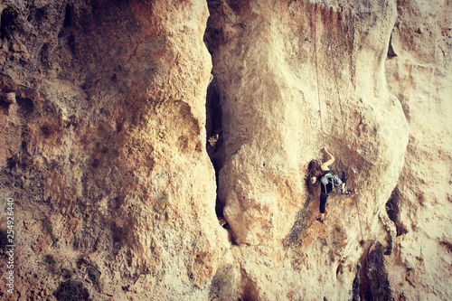 Girl rock climber climbs difficult route on the cliffs