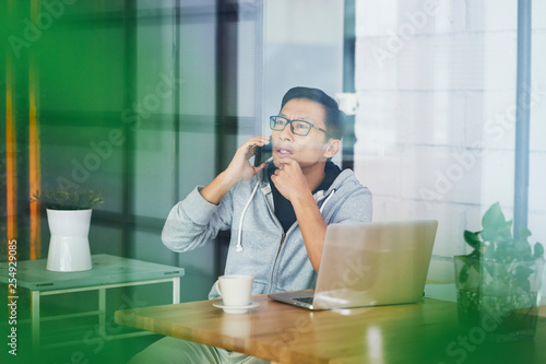Photography Portrait of Asian businessman calling while working on laptop in office