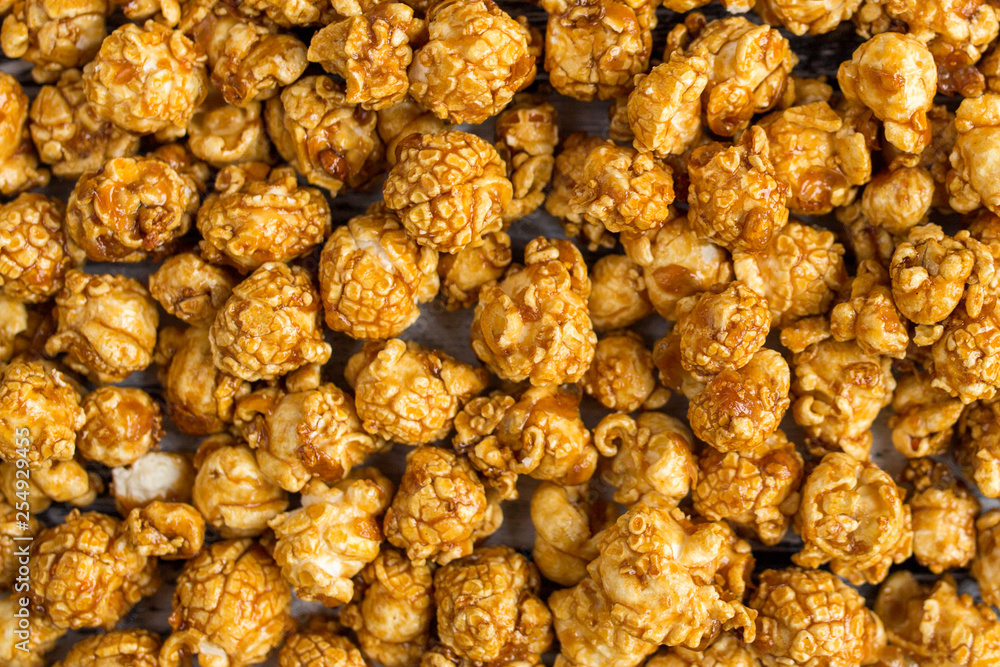 Sweet caramel popcorn in a yellow cup. A tasty snack for watching movies. Sweet caramel popcorn in a yellow cup. A tasty snack for watching movies.