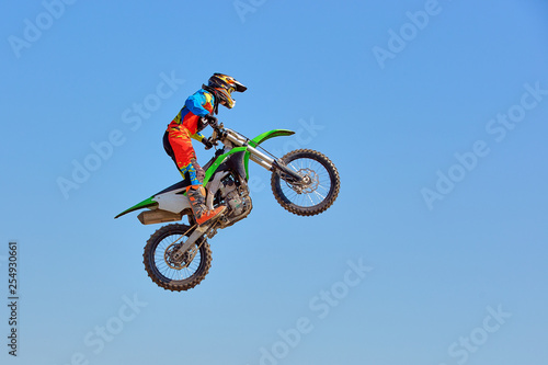 Extreme sports background - silhouette of biker jumping on motorbike on sunset, against the blue sky