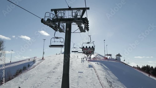 Ski chairlift with people moving up, view at chairlift mechanism photo