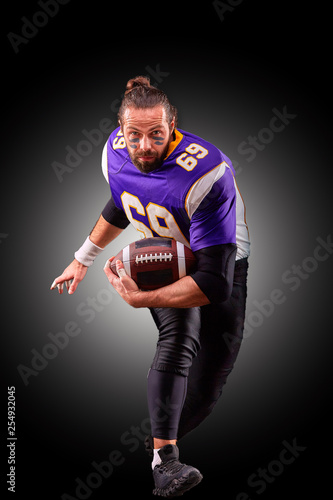Portrait of American football player throwing ball over black background