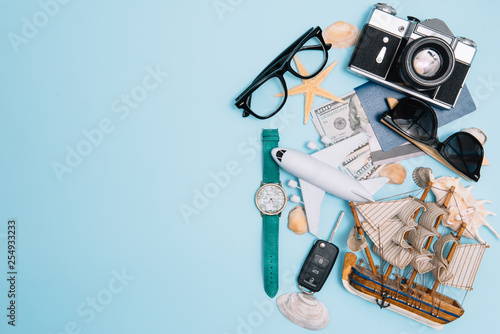 top view travel concept with retro camera films, smartphone, map, passport, compass and Outfit of traveler on blue background with copy space, Tourist essentials, vintage tone effect