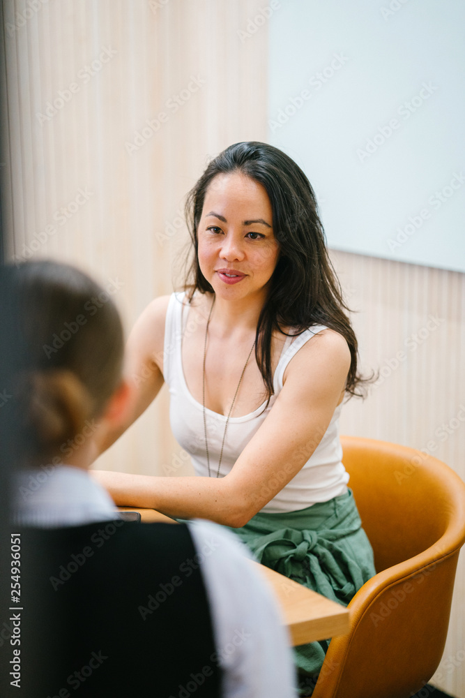 Two magnificent women talking about an article inside a room. They look amazingly capable in their office apparel. Two magnificent women talking about an article inside a room. They look amazingly capable in their office apparel.