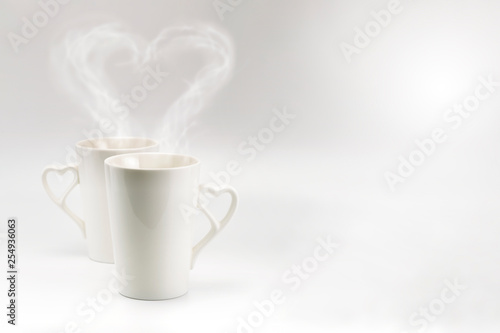 A couple white cup with heart steam and heart handle in horizontal format