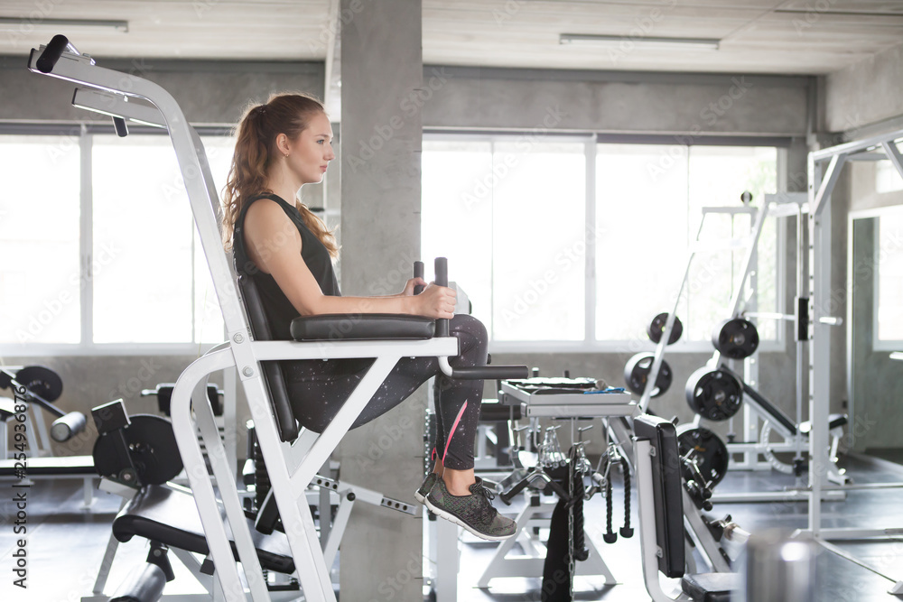 Beautiful young sport woman exercise doing leg raises on abdominal