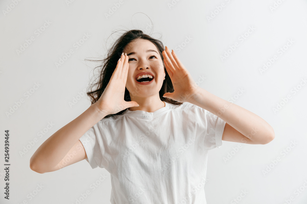 Do not miss. Young casual woman shouting. Shout. Crying emotional woman screaming ongray studio background. Female half-length portrait. Human emotions, facial expression concept. Do not miss. Young casual woman shouting. Shout. Crying emotional woman screaming ongray studio background. Female half-length portrait. Human emotions, facial expression concept.