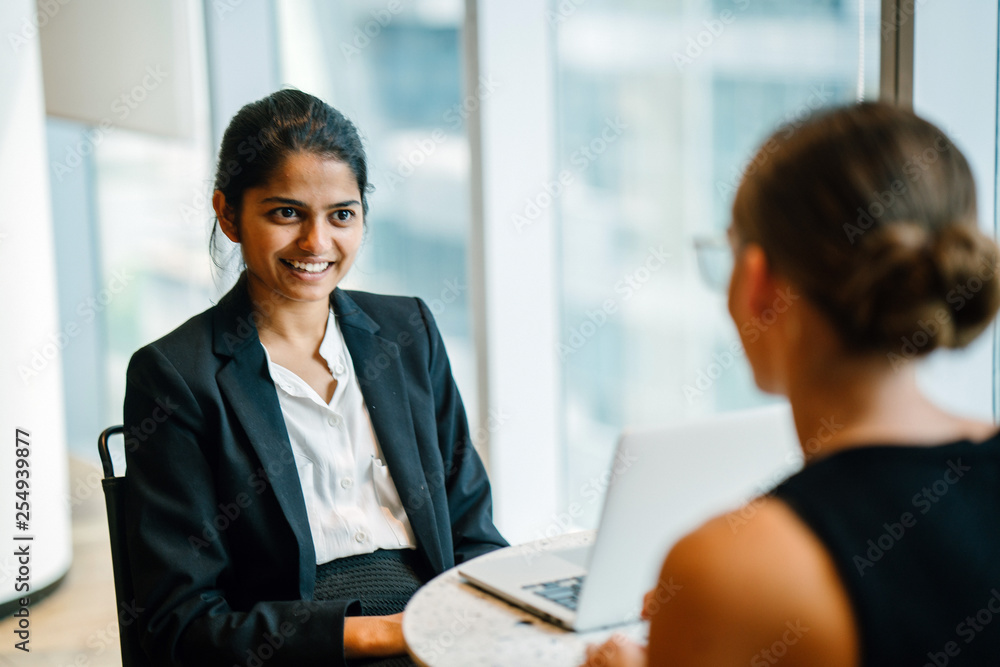 A lovely Indian lady sitting by an accessory inside a cafeteria. She is telling a joke with a colleague. A lovely Indian lady sitting by an accessory inside a cafeteria. She is telling a joke with a colleague.