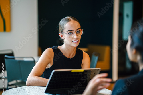 Foto A young Caucasian woman discussing work with a team mate seriously inside a cafeteria