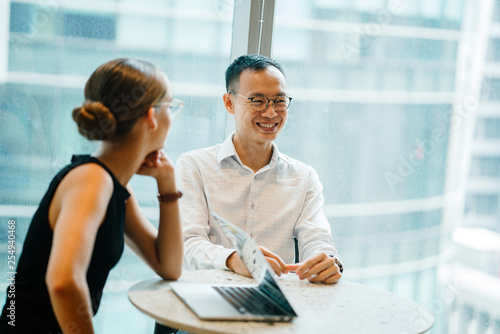 A youthful Asian Chinese ace is giving an introduction before his accomplices in the workplace. He is smiling while discussing the presentation.  photo