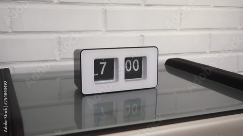 Flip clock mechanism. 7:00 PM. Flip clock watch face. White brick wall in the background. Slow motion 240 fps.