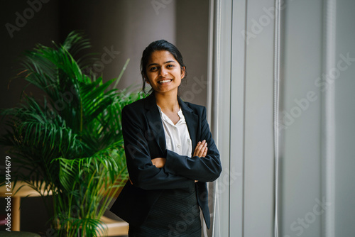 Portrait of a beautiful businesswoman standing in the conference center next to a glass window. She wears a black suit and pants, making her look so professional.
