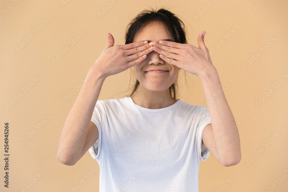 Image of funny chinese woman wearing basic t-shirt covering her eyes with hands Image of funny chinese woman wearing basic t-shirt covering her eyes with hands