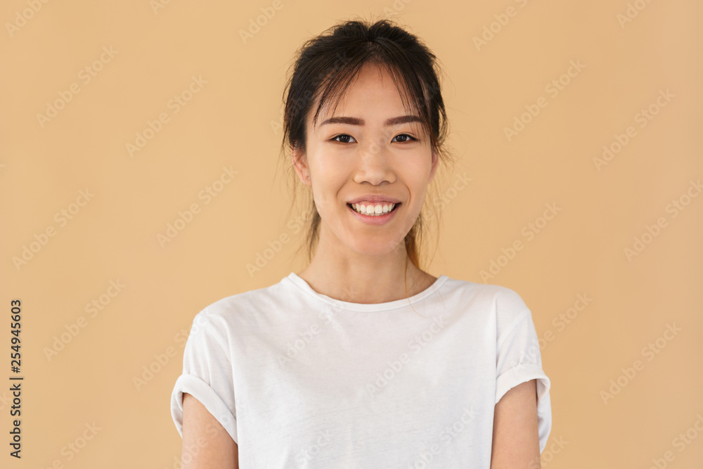 Portrait of positive asian woman wearing basic t-shirt smiling and looking at camera Portrait of positive asian woman wearing basic t-shirt smiling and looking at camera