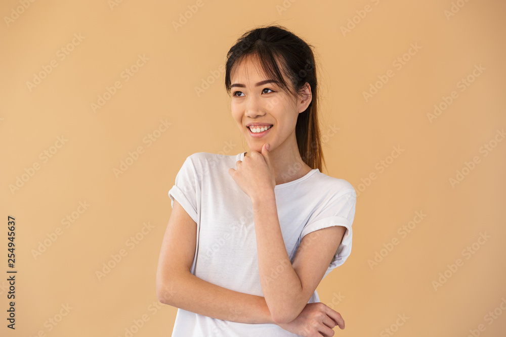 Portrait of cheerful asian woman wearing basic t-shirt smiling and looking aside Portrait of cheerful asian woman wearing basic t-shirt smiling and looking aside