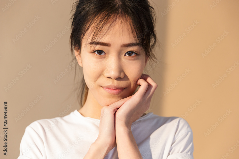Portrait closeup of cute chinese woman wearing basic t-shirt smiling and looking at camera Portrait closeup of cute chinese woman wearing basic t-shirt smiling and looking at camera
