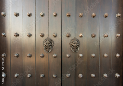 metal Oriental lion handle on teak wood door. antique oriental door knocker.
