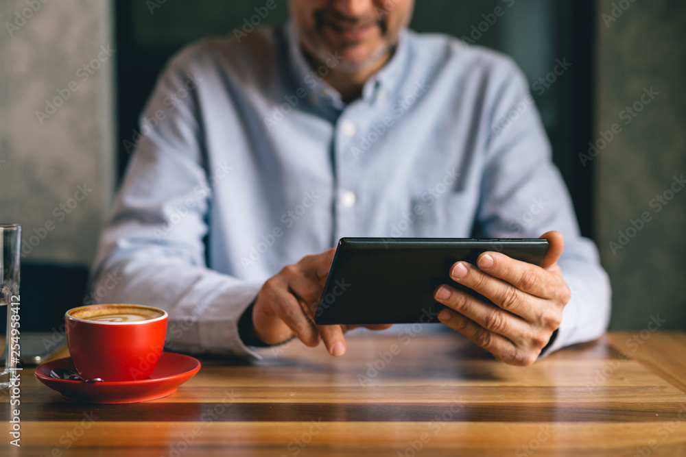 closeup of espresso coffee or cappuccino and blurred man using tablet in background closeup of espresso coffee or cappuccino and blurred man using tablet in background