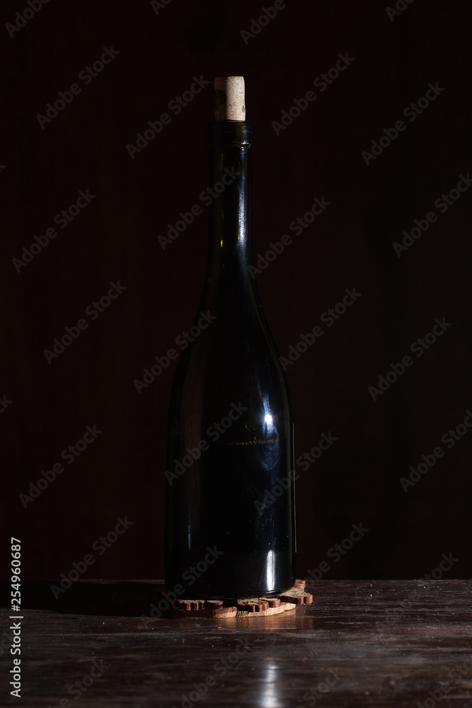 Wine bottle with wineglass in black background.