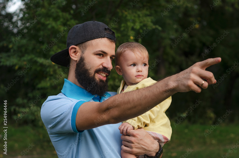 stylish bearded father and his little daughter in his arms while walking in the park stylish bearded father and his little daughter in his arms while walking in the park