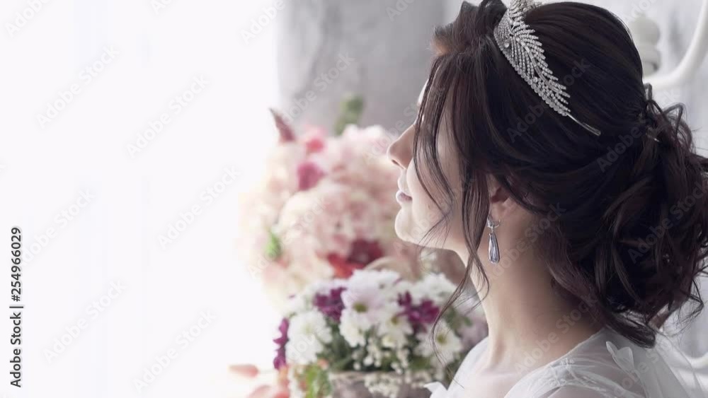 slow motion close view young woman with brilliant tiara and white veil stands at window against flowers slow motion close view young woman with brilliant tiara and white veil stands at window against flowers