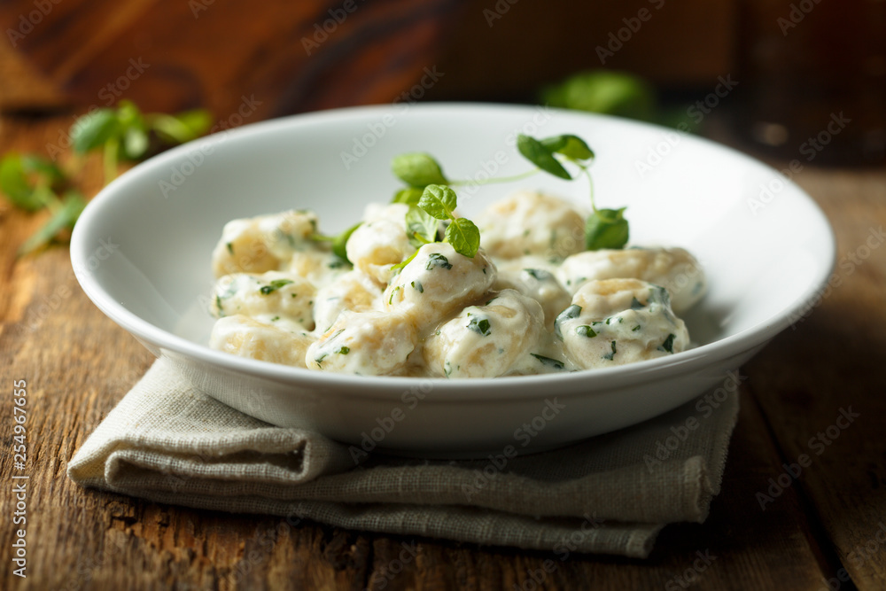 Homemade potato gnocchi with creamy basil sauce