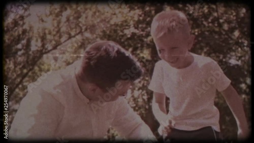 Family video archive. Retro camera 8 mm. Old film. Father with his son blowing soap bubbles, fun family pastime, a child having fun with his dad