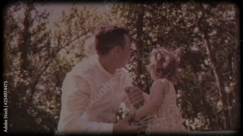 Family video archive. Retro camera 8 mm. Old film. The young father blows soap bubbles with his daughter and son. Family games near the house. Holiday, holidays. Family together
