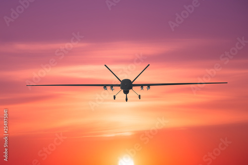 Unmanned military drone patrols the territory at sunset, view is straight ahead.