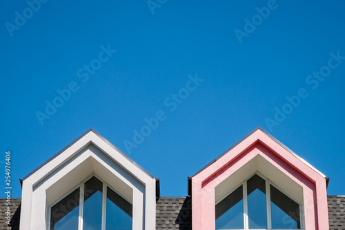 Obraz na plátne Roofline covered with shingle and pointed attic windows against blue sky