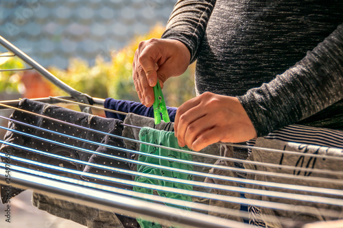 Pregnant woman is hanging on the clothes of her unborn baby on a clothes horse. Concept: family and baby
