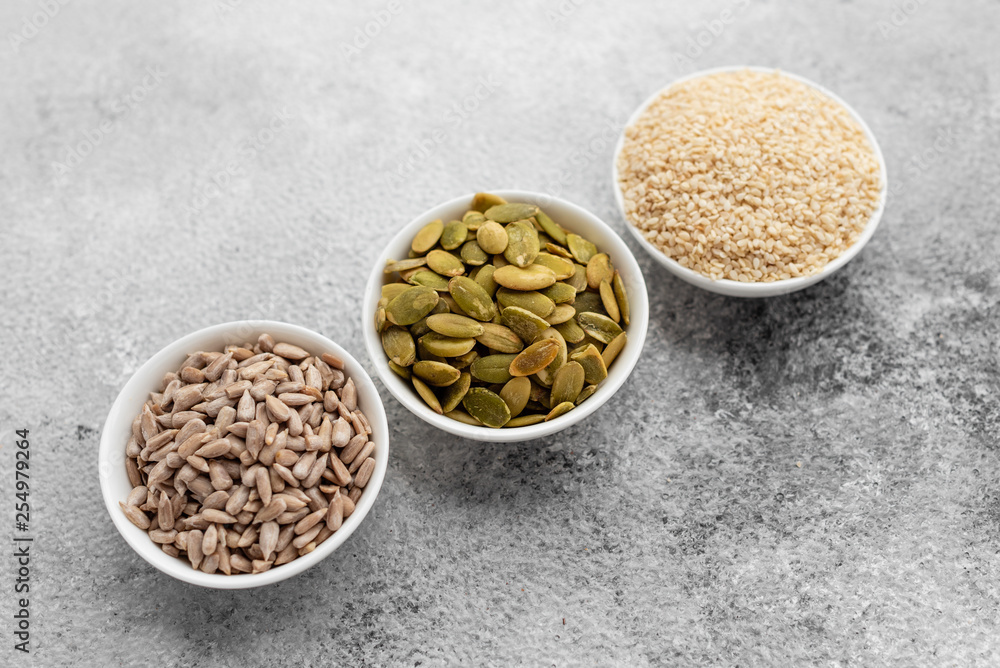 Assortment of nuts in white saucers on a concrete background. Food mix background, top view, copy space, banner Assortment of nuts in white saucers on a concrete background. Food mix background, top view, copy space, banner